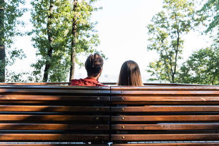 Back view of tourists sitting on bench in cityの写真素材
