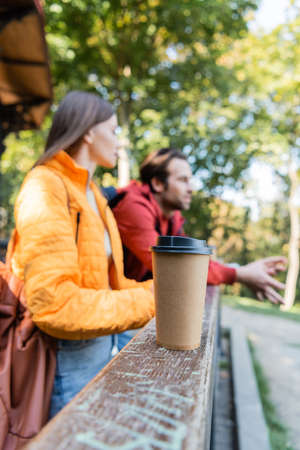 Takeaway drink near blurred couple of tourists outdoors