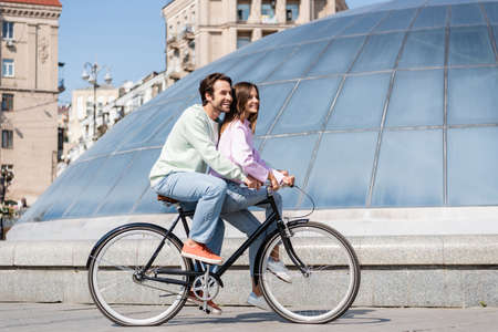 Positive couple of travelers cycling on urban streetの写真素材