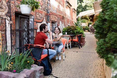 Smiling woman looking at boyfriend drinking coffee to go on terraceの写真素材