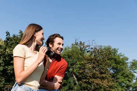 Low angle view of cheerful woman holding binoculars near boyfriend outdoorsの写真素材