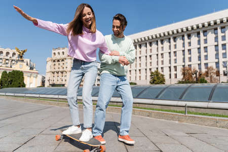 Positive couple riding penny board on urban streetの写真素材