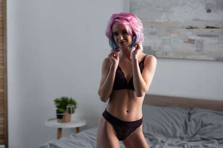 young woman in dark sexy lingerie smiling in bedroomの写真素材