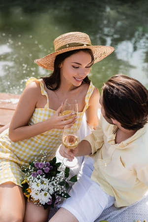 high angle view of romantic couple holding glasses of wine near bouquet of flowers