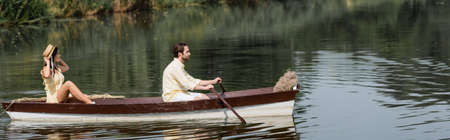 side view of couple having romantic boat ride on lake, bannerの写真素材