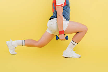 Cropped view of sportsman training with dumbbells on yellow backgroundの写真素材