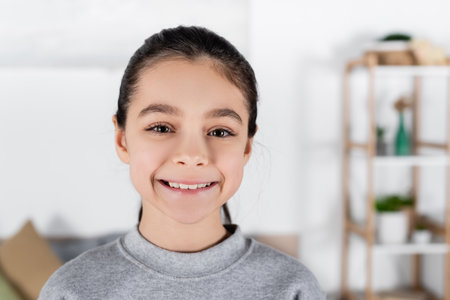 portrait of happy preteen girl looking at camera at homeの写真素材