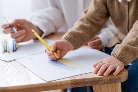 cropped view of patriotic child drawing ukrainian flag near blurred motherの写真素材