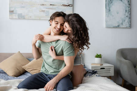 curly woman hugging happy boyfriend with closed eyesの写真素材