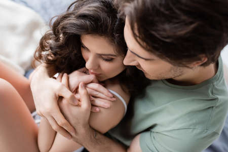 high angle view of man in green t-shirt hugging sensual woman