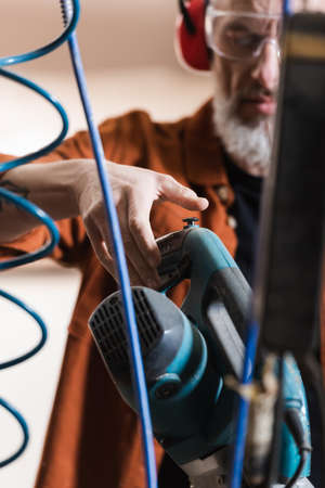 cropped view of blurred carpenter working with miter saw in workshop