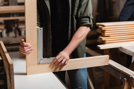 cropped view of furniture designer measuring wooden details with corner rulerの写真素材
