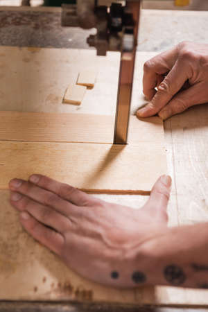 cropped view of joiner cutting plywood with band sawの写真素材