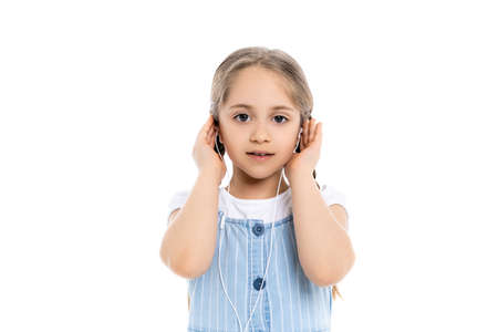 girl looking at camera and adjusting earphones isolated on white