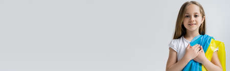 patriotic ukrainian girl with national flag and hands on heart isolated on grey, bannerの写真素材