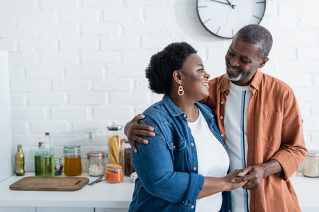 happy senior african american man looking at wife in kitchenの写真素材