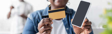 cropped view of senior african american woman holding credit card and smartphone with blank screen,...