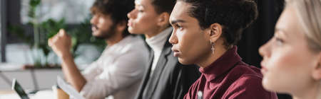 Side view of african american businessman looking away near multiethnic colleagues, banner