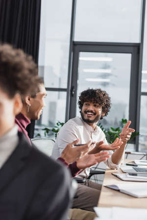 Happy indian businessman talking to african american colleague in officeの写真素材
