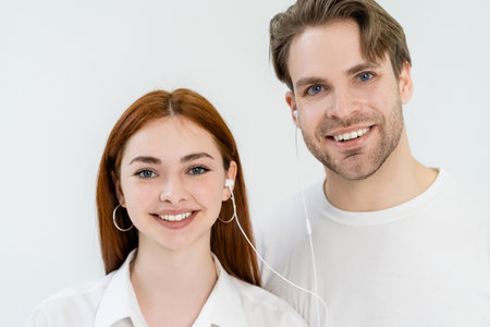 Smiling couple listening music in earphones isolated on whiteの写真素材