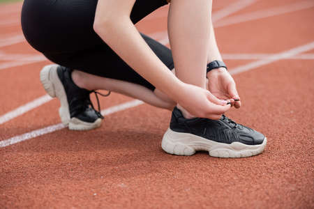 cropped view of sportswoman lacing black sneakerの写真素材