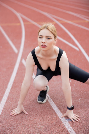 pretty young woman in black sportswear exercising on stadiumの写真素材