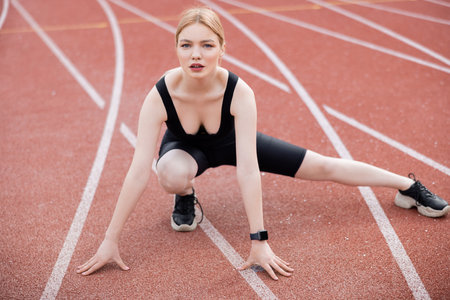 full length view of woman in black sportswear exercising on athletic fieldの写真素材
