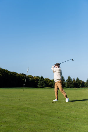senior man in flat cap playing golfの写真素材