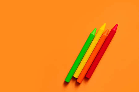 top view of colorful crayons on orange background