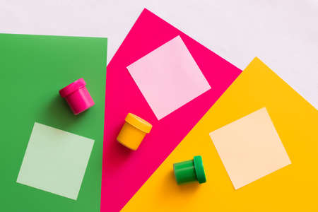 top view of multicolored jars with paint near paper notes on colorful background