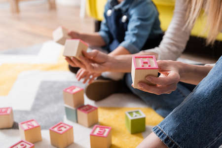 Cropped view of speech therapist holding wooden blocks with letters near lid in consulting roomの写真素材