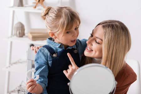 Positive speech therapist pointing at pupil with letter near mirror in classroomの写真素材