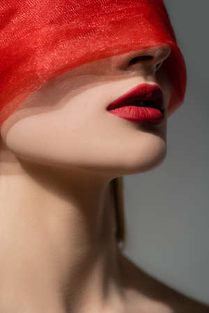 Woman with red lips and cloth on face posing isolated on greyの写真素材