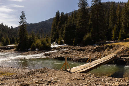 Wooden bridge above river in mountainsの写真素材