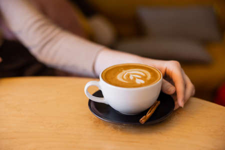 cropped view of young woman near cup of cappuccinoの写真素材
