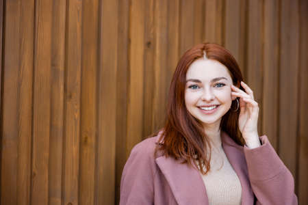 happy young woman with red hair smiling outdoors