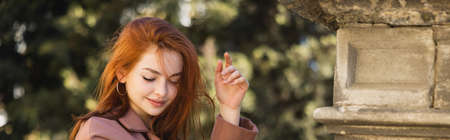young happy redhead woman in coat posing outside, bannerの写真素材