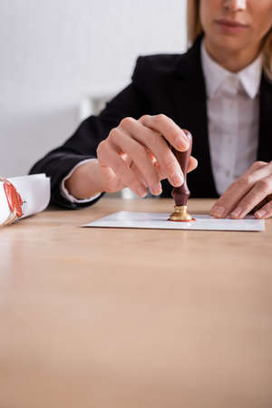partial view of notary sealing envelope with wax near rolled contract