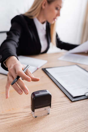 lawyer reaching stamper while working with documents on blurred background