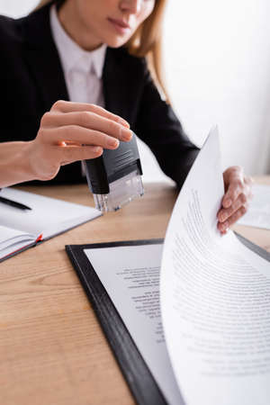 partial view of lawyer holding stamper near contract on blurred backgroundの写真素材