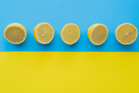 Top view of ripe halves of lemons on blue and yellow backgroundの写真素材