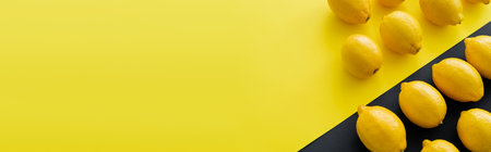 Flat lay with organic lemons on yellow and black surface, banner