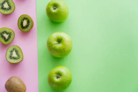 top view of rows with ripe apples and kiwi fruits on green and pinkの写真素材