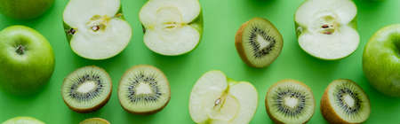 flat lay of apples and kiwi fruits halves on green, bannerの写真素材