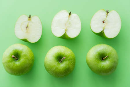 flat lay of tasty whole and cut apples on greenの写真素材