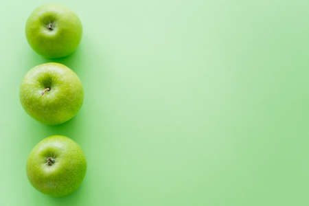 top view of row with fresh apples on greenの写真素材