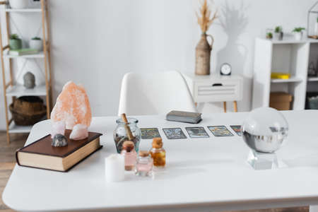 KYIV, UKRAINE - FEBRUARY 23, 2022: Glass orb, magic crystals and tarot cards on table