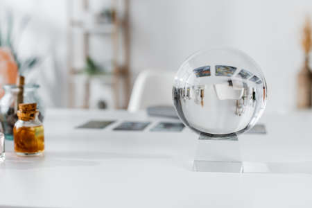 Glass orb near blurred witchcraft supplies on tableの写真素材