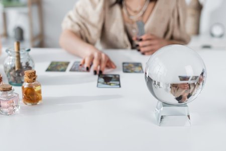 Cropped view of glass orb near blurred fortune teller with tarot cardsの写真素材