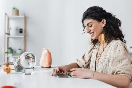 Smiling gypsy fortune teller looking at tarot cards at home